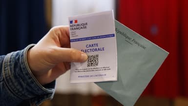 Une persone montre sa carte électorale et une enveloppe de vote lors du premier tour des élections législatives, le 30 juin 2024.