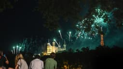 Des Lyonnais regardent un feu d'artifice au-dessus de Notre-Dame de Fourvière le 14 juillet 2023