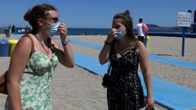 Deux femmes remettent leur masque en revenant de la plage - même s'il n'est pas obligatoire - à Argeles-sur-Mer (sud de la France), le 17 juillet 2021