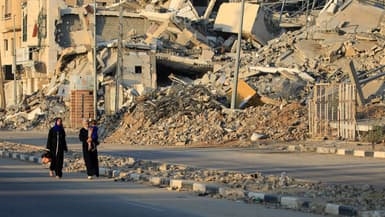 Des Palestiniens déplacés passent devant des bâtiments détruits dans le camp de réfugiés d'al-Bureij, dans le centre de la bande de Gaza, le 12 juin 2024, au milieu du conflit en cours entre Israël et le groupe militant du Hamas. PHOTO D'ILLUSTRATION