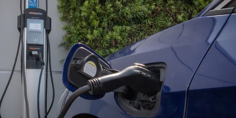 Une voiture électrique branchée sur une bore de recharge.