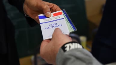 Un homme tend sa carte d'électeur dans un bureau de vote à Marseille, le 25 mai 2019, lors des élections européennes.