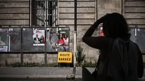 Une femme passe devant des panneaux électoraux avant les législatives à Bordeaux le 25 juin 2024