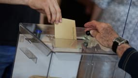 Une personne dépose son bulletin de vote dans une urne à Saint-Savin, le 12 juin 2022